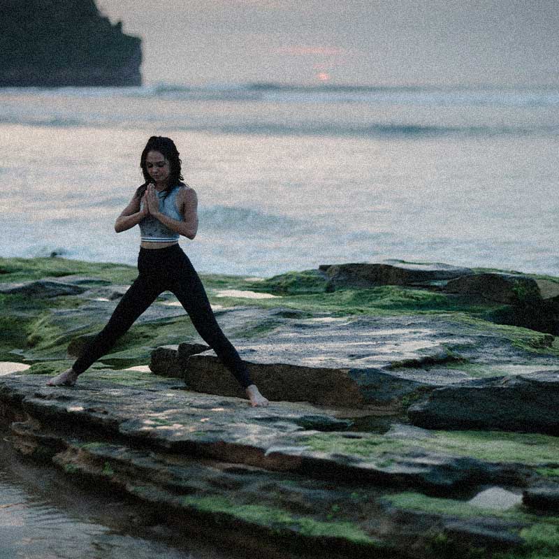 femme qui pratique du yoga près de la mer